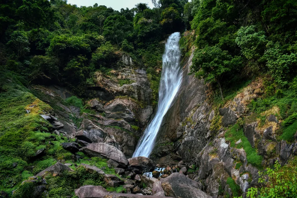 Phamrong Waterfall Yuksom - dramatic cascading waterfall surrounded by moss-covered rocks and lush green forests near Yuksom sightseeing circuit