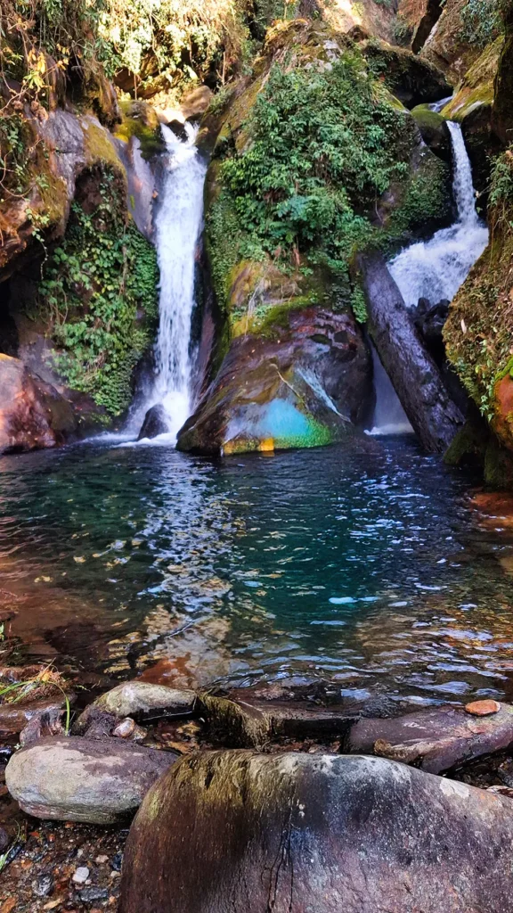 Elephant Falls near Tsong village Yuksom - hidden waterfall with emerald pool surrounded by moss-covered rocks and lush vegetation, accessible near Dubdi Monastery
